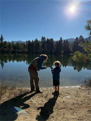 Picture of a woman teaching a young boy how to fish by a lake