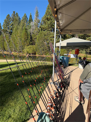 A row of fishing poles lined up along the side of a canopy tent in preparation for the Lake Baron Fishing Derby